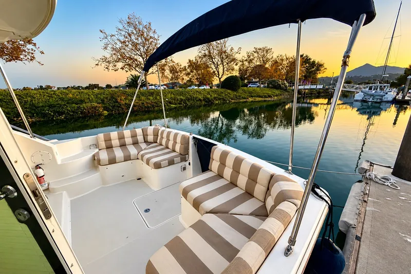 Slide: The Image of 2011 Back Cove 37 boat with striped seating, docked at sunset by a tranquil waterway. - 6