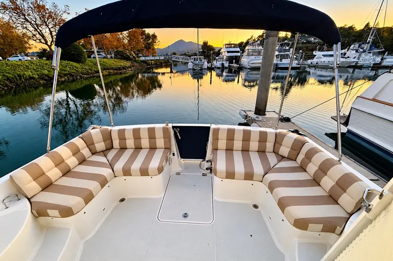 Slide: The Image of 2011 Back Cove 37 boat with striped seating, docked at sunset in a serene marina. - 8