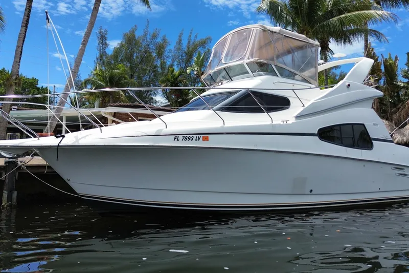 Slide: The Image of 2002 Silverton 330 Sport Bridge yacht docked by palm trees and clear sky. - 62
