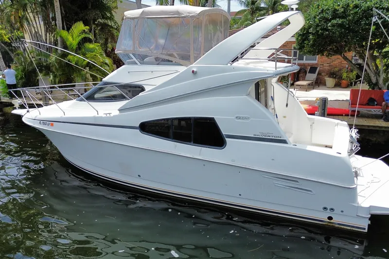 Slide: The Image of 2002 Silverton 330 Sport Bridge yacht docked by lush greenery. - 54
