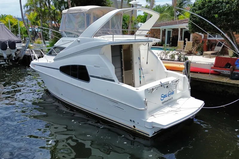 Slide: The Image of 2002 Silverton 330 Sport Bridge yacht docked in a serene waterfront setting. - 53