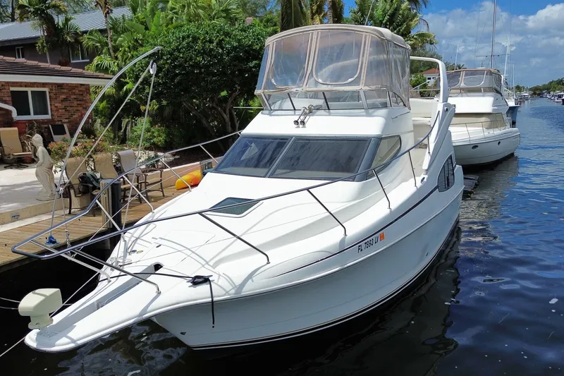 Slide: The Image of 2002 Silverton 330 Sport Bridge yacht docked by a lush, tropical waterfront. - 56