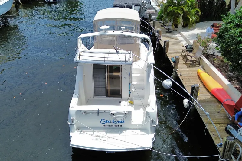 Slide: The Image of 2002 Silverton 330 Sport Bridge docked by a waterfront with lush greenery. - 52