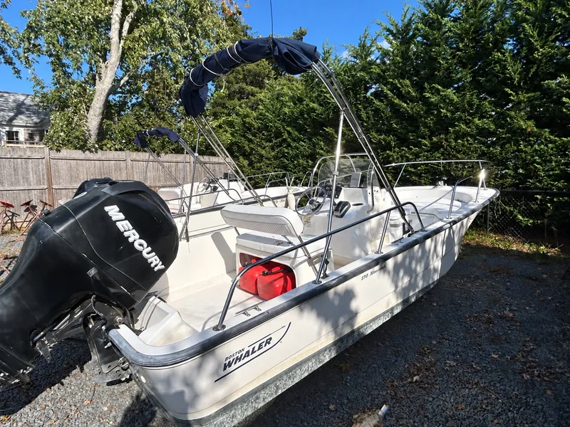 Slide: The Image of A 2007 Boston Whaler 17 Montauk on a gravel lot. It features a Mercury outboard motor. - 6