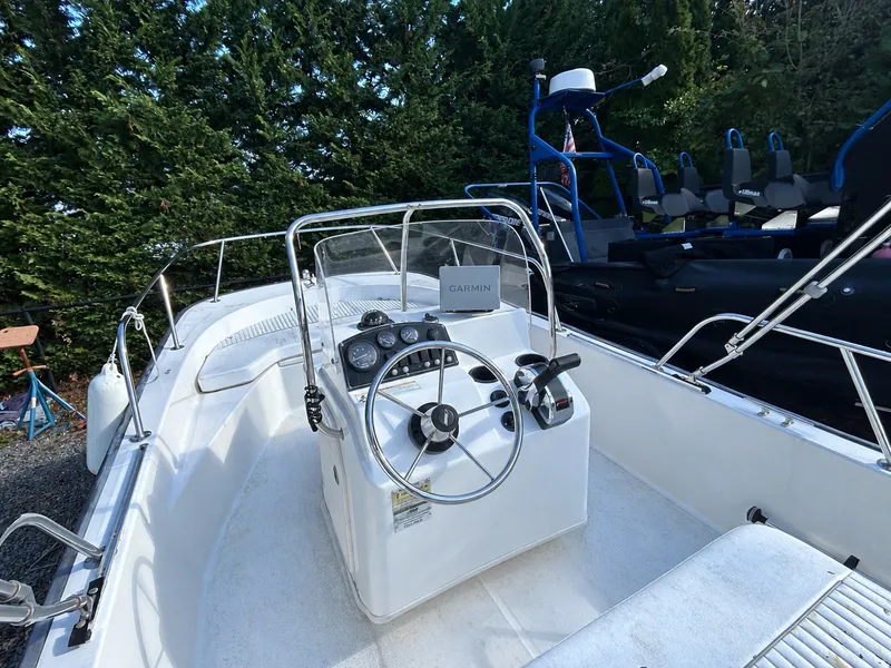 Slide: The Image of A 2007 Boston Whaler 17 Montauk with a helm and Garmin navigation, surrounded by trees. - 5