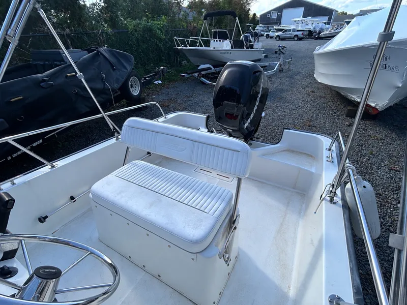 Slide: The Image of A 2007 Boston Whaler 17 Montauk with white seating and helm, parked on a gravel lot. - 4