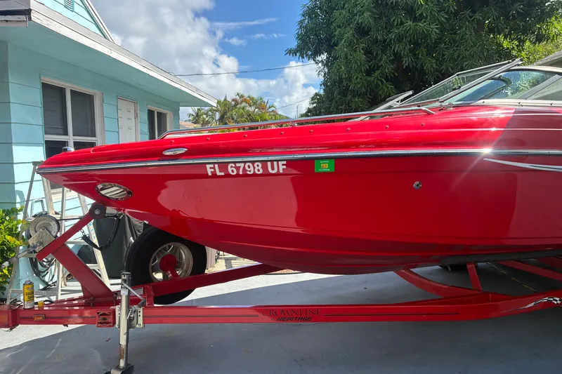 The Image of Red 2007 Crownline 23 SS boat on trailer, parked beside a blue house. - 0