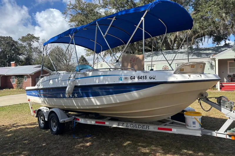 Slide: The Image of 2006 Bayliner 210 Classic boat on trailer with blue canopy, parked outdoors. - 1