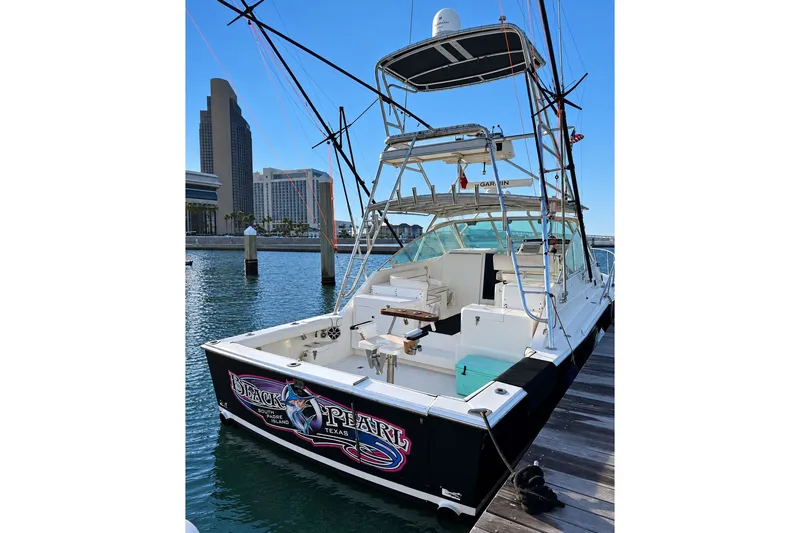 Slide: The Image of 1995 Cabo 35 Express boat docked, featuring a spacious deck and fishing equipment. - 1