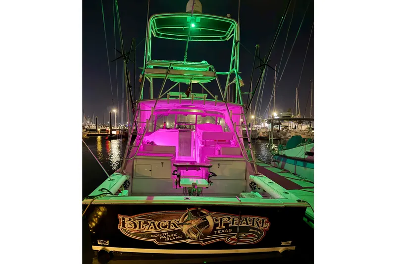 Slide: The Image of 1995 Cabo 35 Express boat with vibrant green and pink lights at night in a marina. - 2