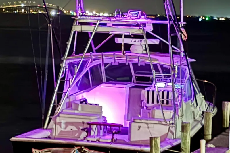 Slide: The Image of 1995 Cabo 35 Express boat docked at night with purple interior lighting. - 3