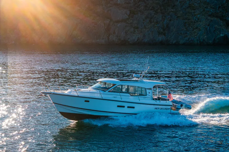 Slide: The Image of 2024 Nimbus 365 Coupe cruising on sunlit water near rocky shoreline. - 28