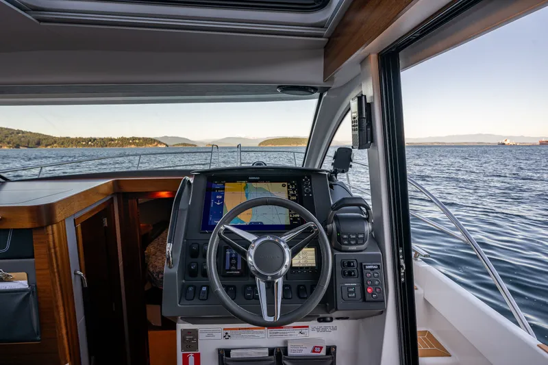 Slide: The Image of Interior view of 2024 Nimbus 365 Coupe helm with navigation system, overlooking serene waters. - 15
