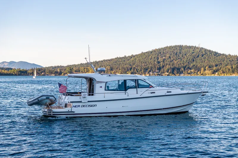Slide: The Image of 2024 Nimbus 365 Coupe boat on serene lake with forested hills in background. - 37