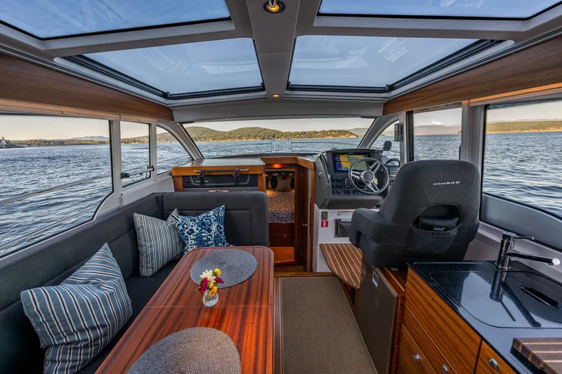 Slide: The Image of Interior of 2024 Nimbus 365 Coupe boat with panoramic windows and elegant seating area. - 5