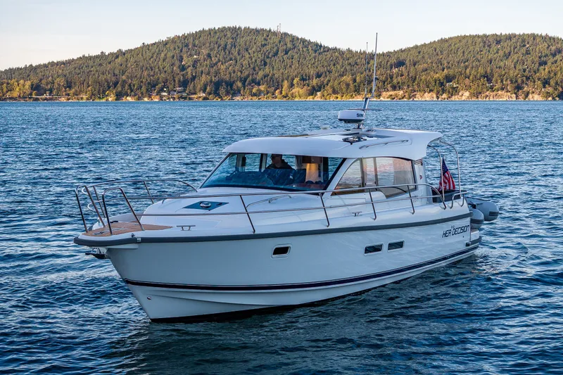 Slide: The Image of 2024 Nimbus 365 Coupe cruising on a scenic lake with forested hills in the background. - 38