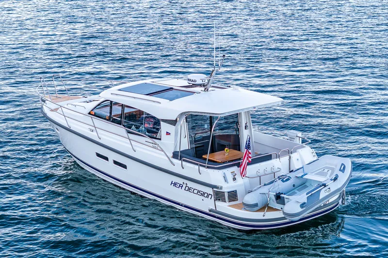 Slide: The Image of 2024 Nimbus 365 Coupe yacht cruising on open water with attached dinghy. - 2