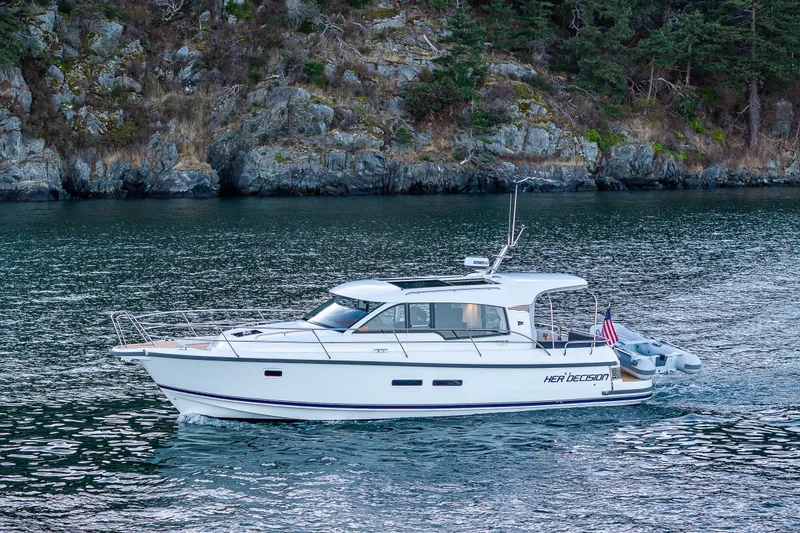 Slide: The Image of 2024 Nimbus 365 Coupe cruising on a scenic waterway with rocky shoreline backdrop. - 40