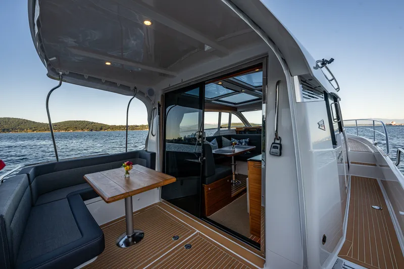 Slide: The Image of 2024 Nimbus 365 Coupe yacht interior with seating and table, overlooking serene waters. - 24