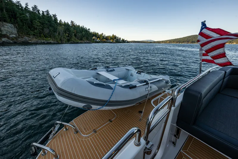 Slide: The Image of 2024 Nimbus 365 Coupe yacht with inflatable boat on scenic waterway. - 25
