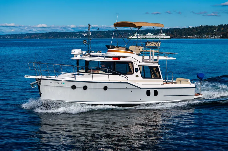 Slide: The Image of 2023 Ranger Tugs R-29 CB cruising on a clear blue lake with scenic background. - 43