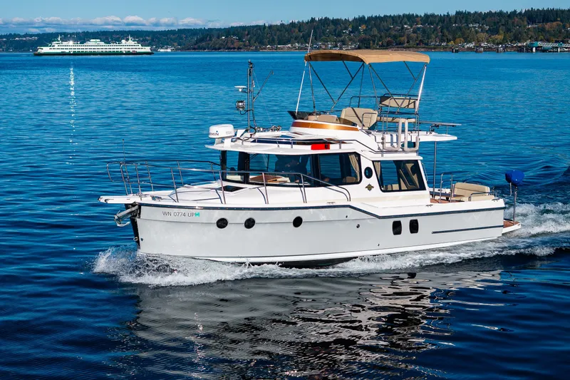 Slide: The Image of 2023 Ranger Tugs R-29 CB cruising on a serene lake with distant ferry. - 42