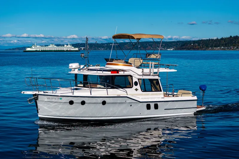Slide: The Image of 2023 Ranger Tugs R-29 CB cruising on a serene blue lake with distant ferry. - 41
