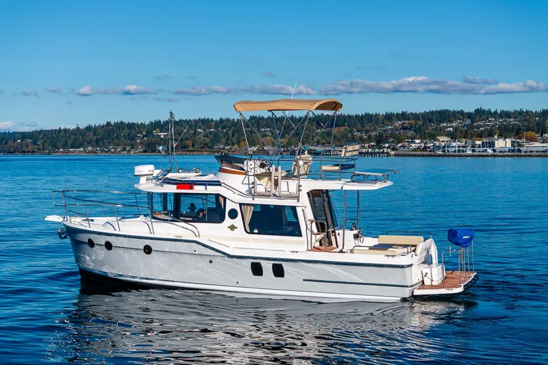 Slide: The Image of 2023 Ranger Tugs R-29 CB boat cruising on a calm lake under a clear blue sky. - 34