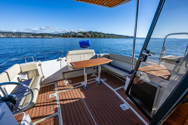 Slide: The Image of 2023 Ranger Tugs R-29 CB boat interior with seating and table on a sunny day. - 21