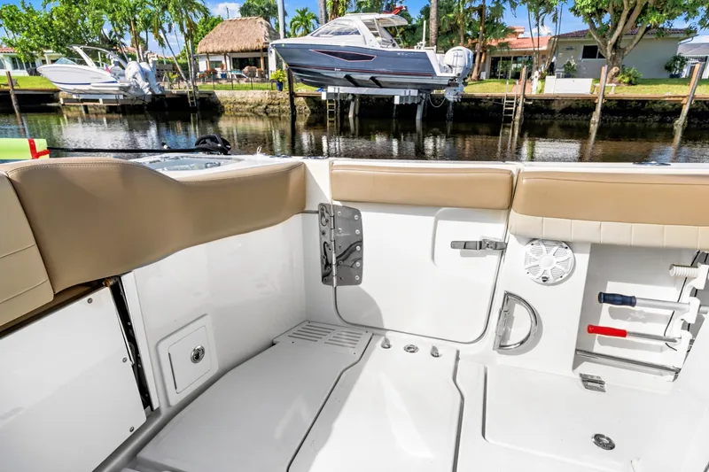 Slide: The Image of 2019 Sailfish 360 CC boat interior with tan seating, docked near waterfront homes. - 18