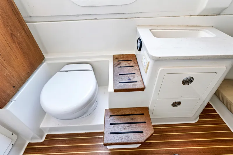 Slide: The Image of 2019 Sailfish 360 CC boat interior with toilet, sink, and wooden steps. - 35