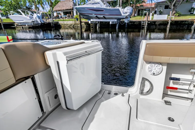 Slide: The Image of 2019 Sailfish 360 CC boat interior with seating and storage, docked by a waterfront. - 17