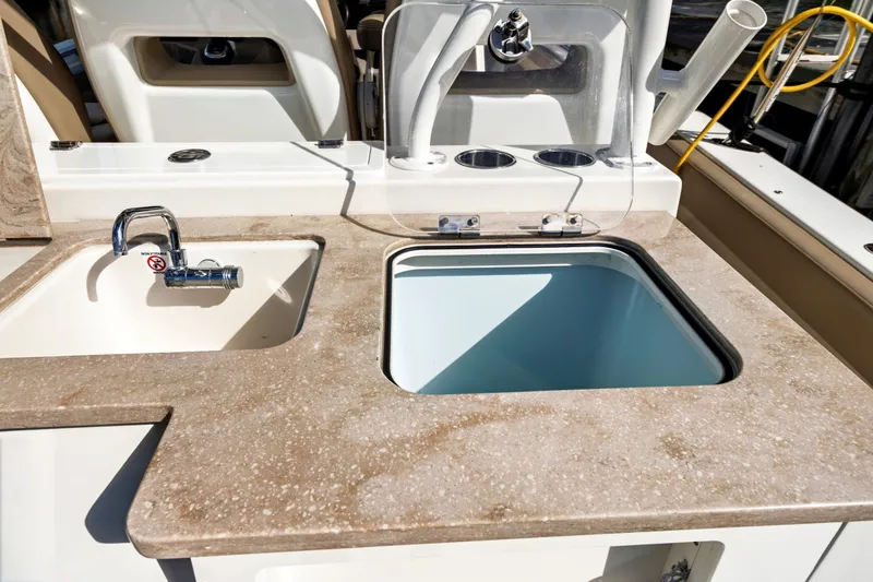 Slide: The Image of 2019 Sailfish 360 CC boat sink and storage area with beige countertop. - 24