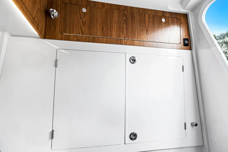 Slide: The Image of Interior storage compartments on 2019 Sailfish 360 CC boat, featuring wood and white finishes. - 32