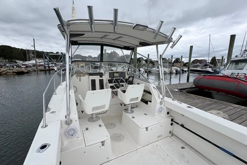 Slide: The Image of 1998 Boston Whaler 235 Conquest boat docked at marina, featuring dual seats and steering console. - 10