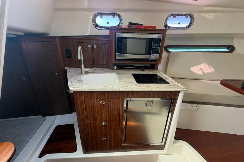 Slide: The Image of 2017 Pursuit OS 325 Offshore boat interior with kitchenette, featuring sink, microwave, and stove. - 41