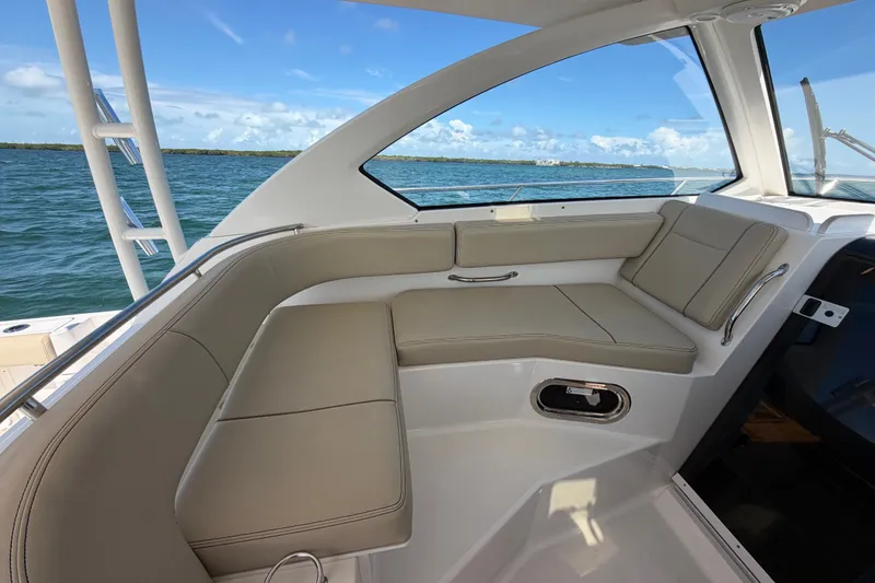Slide: The Image of Interior view of 2017 Pursuit OS 325 Offshore boat with beige seating and ocean backdrop. - 23