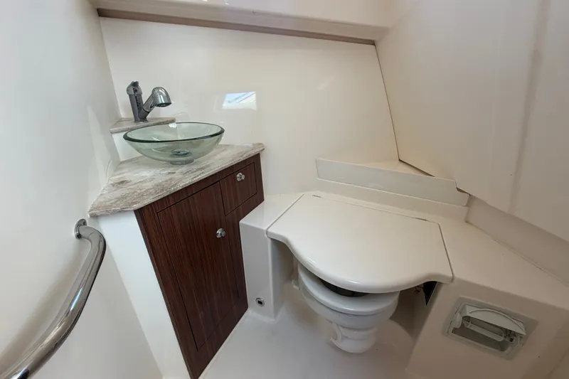 Slide: The Image of 2017 Pursuit OS 325 Offshore boat bathroom with glass sink and compact toilet. - 39