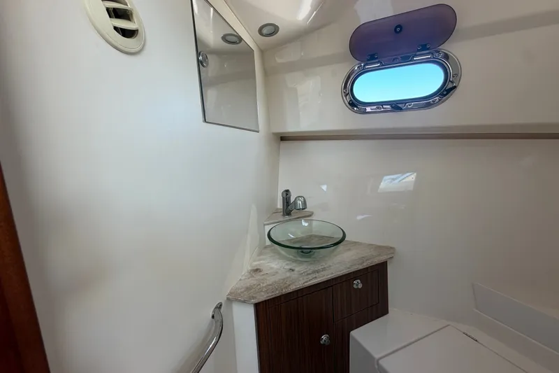 Slide: The Image of Interior of 2017 Pursuit OS 325 Offshore boat bathroom with glass sink and porthole window. - 40
