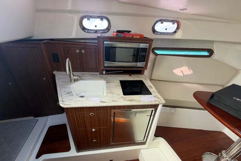 Slide: The Image of 2017 Pursuit OS 325 Offshore boat interior with kitchenette, featuring sink, microwave, and stove. - 42