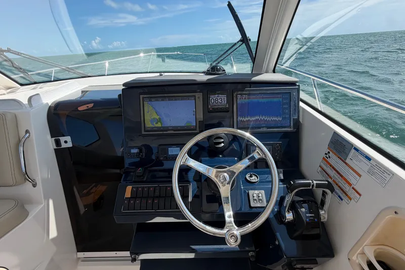 Slide: The Image of Helm of 2017 Pursuit OS 325 Offshore boat with navigation screens and steering wheel. - 26