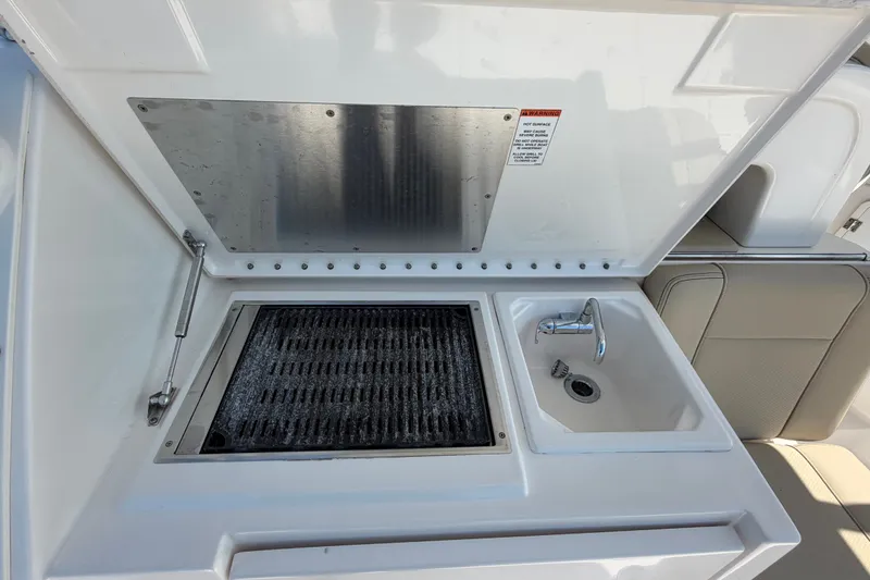 Slide: The Image of Outdoor kitchen setup on a 2017 Pursuit OS 325 Offshore boat, featuring a grill and sink. - 18