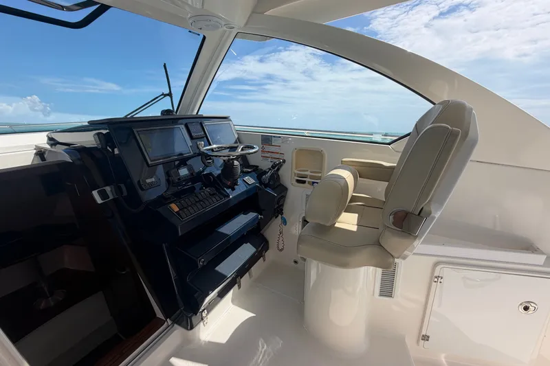 Slide: The Image of 2017 Pursuit OS 325 Offshore boat cockpit with steering wheel and navigation screens. - 49