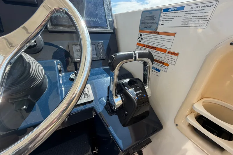 Slide: The Image of 2017 Pursuit OS 325 Offshore helm with Yamaha controls and safety notices. - 29