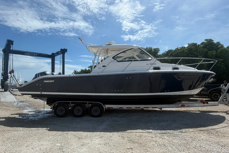 Slide: The Image of 2017 Pursuit OS 325 Offshore boat on trailer, parked outdoors under a clear sky. - 8