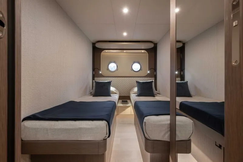 Slide: The Image of The 2028 Absolute Navetta 58 cabin features two single beds with blue blankets. - 19