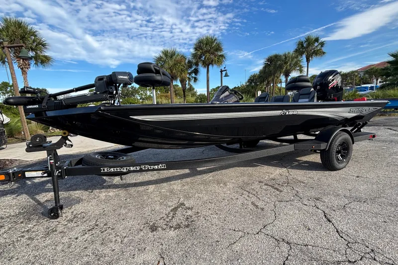 Slide: The Image of 2027 Ranger RT188 boat on trailer, parked outdoors with palm trees and blue sky. - 1