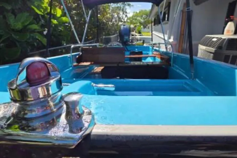 Slide: The Image of 1973 Boston Whaler 13 Sport boat with blue interior and chrome details, docked outdoors. - 13