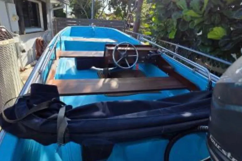 Slide: The Image of 1973 Boston Whaler 13 Sport boat with blue interior and wooden accents, parked outdoors. - 11