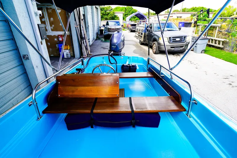 Slide: The Image of 1973 Boston Whaler 13 Sport boat with wooden seats and blue interior, parked outdoors. - 13
